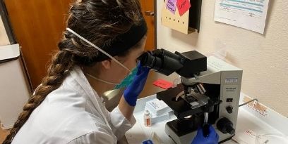 Resident looking through a microscope (c) UC Regents. All rights reserved.