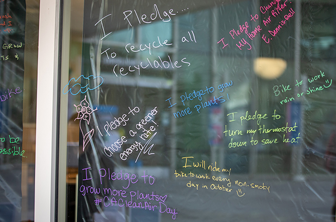 Employee green day pledges written in colorful grease pencil on a window