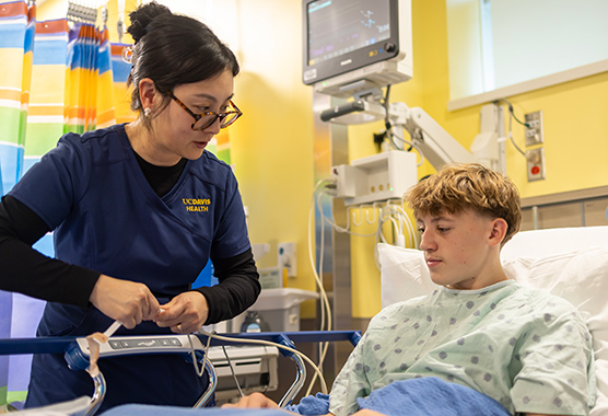 Pediatric nurse caring for a teenage patient in a hospital room