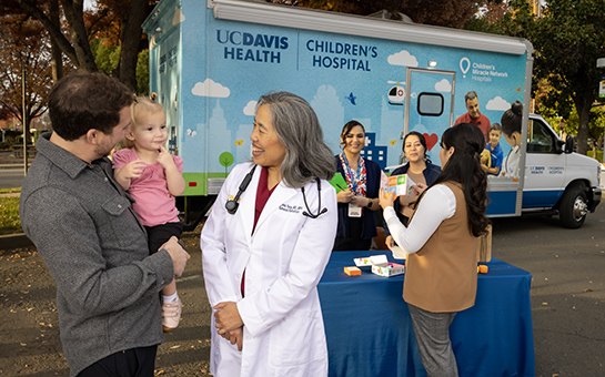 Parent holding child next to pediatrician Serena Yang at the UC Davis pediatric mobile clinic