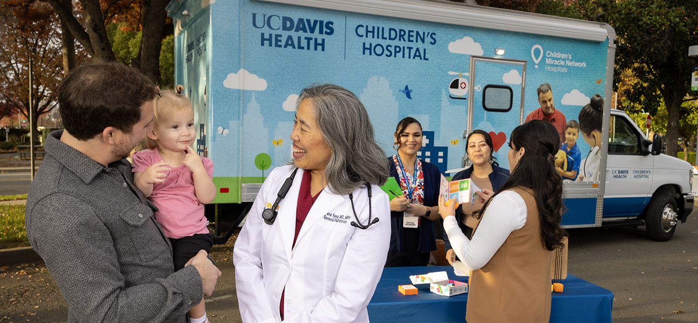 Parent holding child next to pediatrician Serena Yang at the UC Davis pediatric mobile clinic