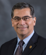Xavier Becerra smiles in a dark suit and tie.