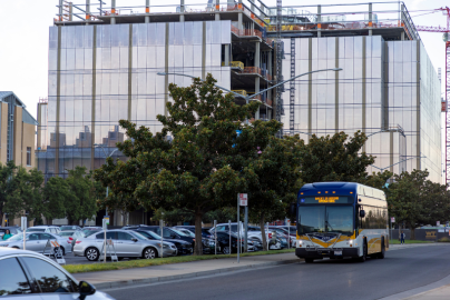 A bus drives down a street in front of a tall glass building.