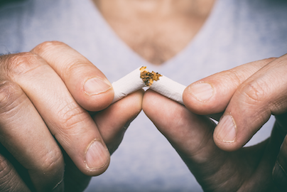 Person breaking a cigarette in half.