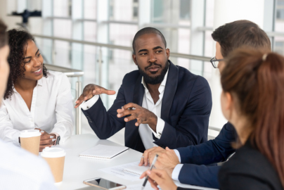 People dressed in professional clothes in discussion around a table.