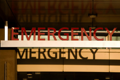An "emergency" sign in show above glass doors to a building.