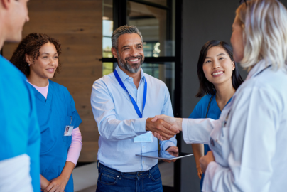Five healthcare professionals gather in a modern hallway with wood-paneled walls and glass doors.