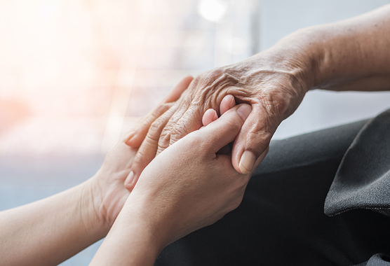 Close up of two people holding hands.