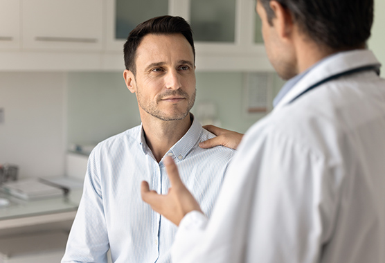 Man with azoospermia talking with urologist in clinic.