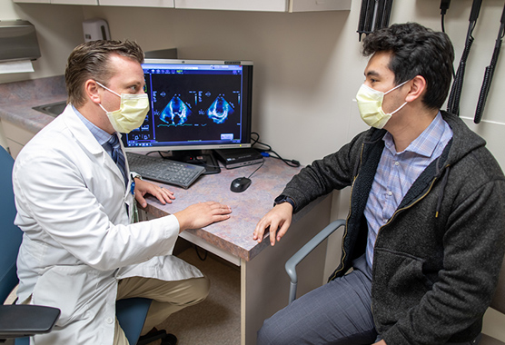 Health care provider listening to male patient’s heart.