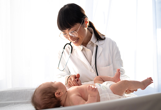 Pediatrician smiling down at baby on a clinic table while discussing undescended testicles.