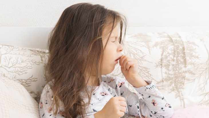 A child in bed coughing.