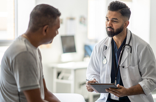 A male doctor speaks to a patient about infertility. 