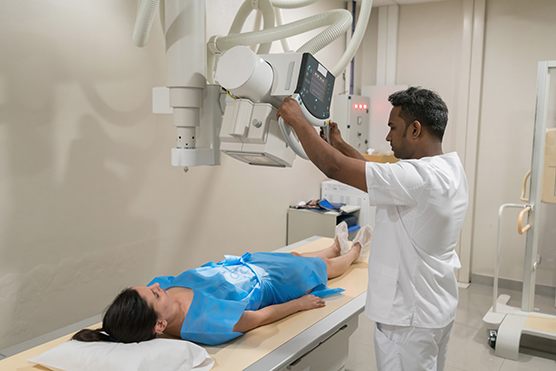 X-ray technician position machine above patient laying on a table.