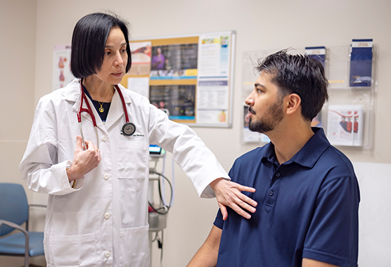 Female nurse listening with a stethoscope to male patient’s heart in a medical clinic 