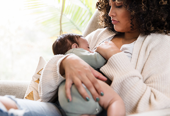 Mother sitting in a chair breastfeeding her baby.