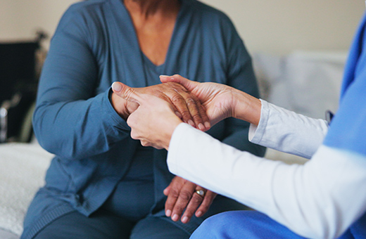Hand surgeon holding a patient’s hand and talking before surgery.