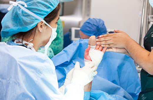 Hand surgeon looking at patient’s hand in operating room.