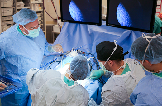 Surgeons performing shoulder replacement on patient.