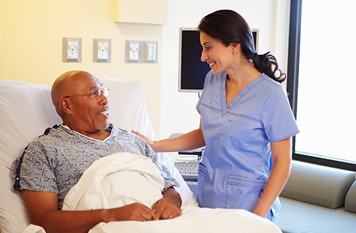 A female nurse smiles at a male patient recovering from urostomy surgery.