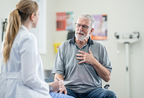 A female doctor speaks with an older man about urostomy surgery.