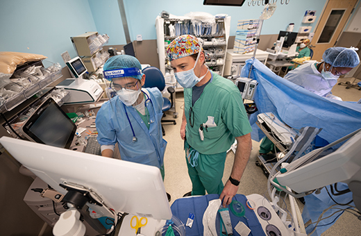 Surgeons looking at computer screen during vascular neurosurgery.