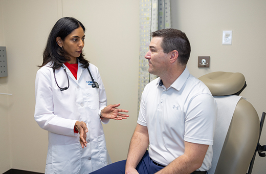 A male patient sits in an exam chair while a doctor discusses surgery.