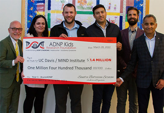 A group of five people holds a large plastic check for $1.4 million dollars for a UC Davis MIND Institute research program.