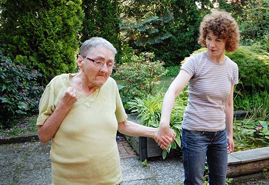 Woman with female senior walking in an outside garden