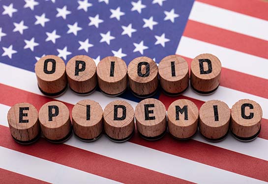 Elevated view of Opioid Epidemic text on wooden cork over American flag