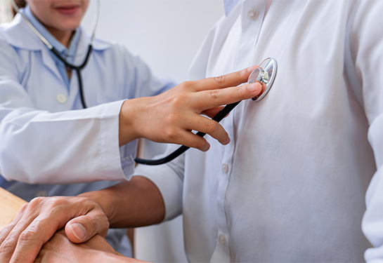 A doctor examines a patient with a stethoscope on the patient’s chest.