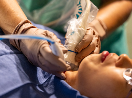 A clinician performs a thyroid procedure on a patient’s neck using an ultrasound-guided device.