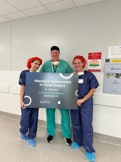 Three people in surgical attire stand in a hallway holding a sign that reads “Milestone Achievement in Sleep Surgery.”