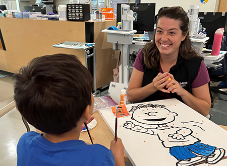 A patient paints with a child life specialist in the hospital