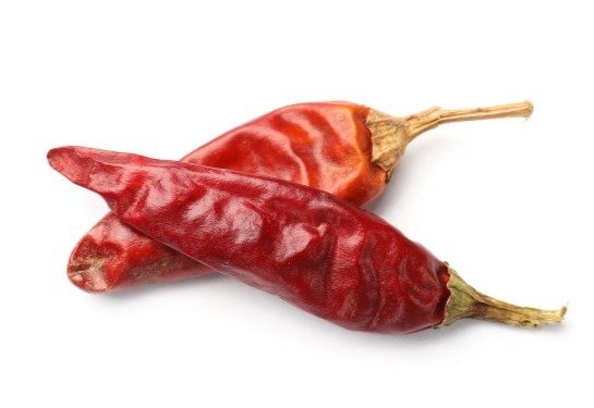 Two dried red chili peppers, a natural source of capsaicin, on a white background.