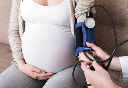 Pregnant person getting blood pressure checked on arm.