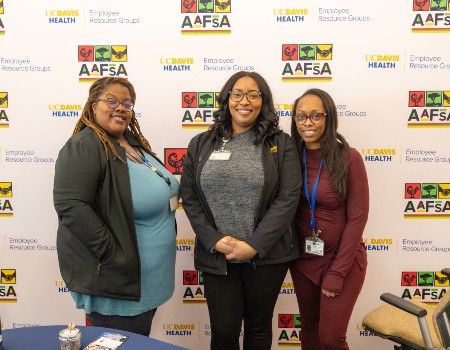 Three black women smiling as they pose for a group photo at a celebratory event