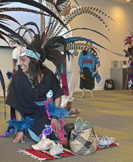 Woman from the Sacramento’s White Hawk Indian Council for Children kneeling on the floor with a bright smile on her face