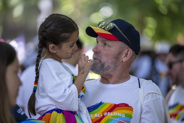 Adult and child wearing UC Davis Health Pride shirts interact during a Pride event.