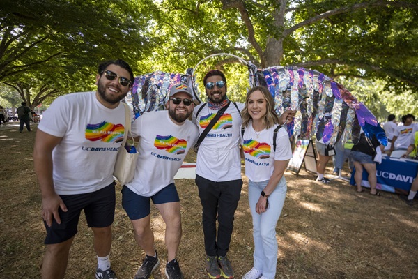 Group of UC Davis Health employees wearing Pride T-shirts pose together at a Pride event.
