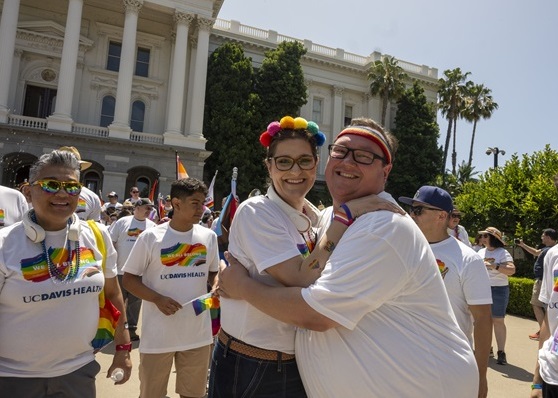 UC Davis Health employees wearing Pride T-shirts stand together in front of the California State Capitol.