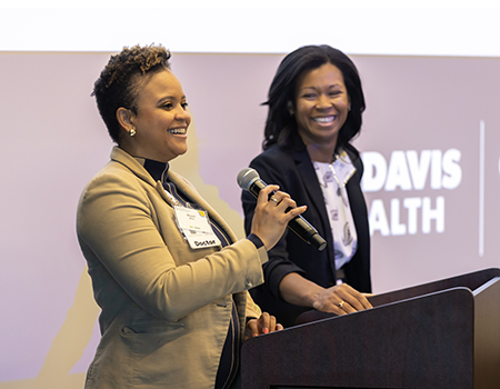 Two women at a podium with large screen behind them that reads “UC Davis Health”.