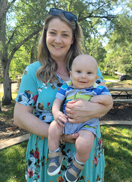 Mom in a green dress holding baby in a striped shirt