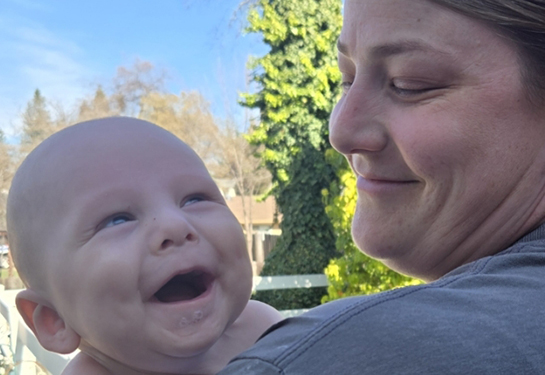 Smiling baby held by mom.