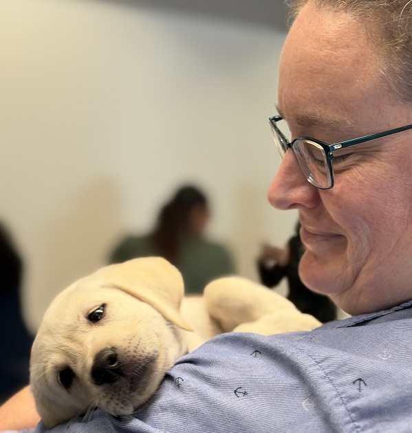 A UC Davis Health employee holds a sleeping Labrador retriever puppy during the event.