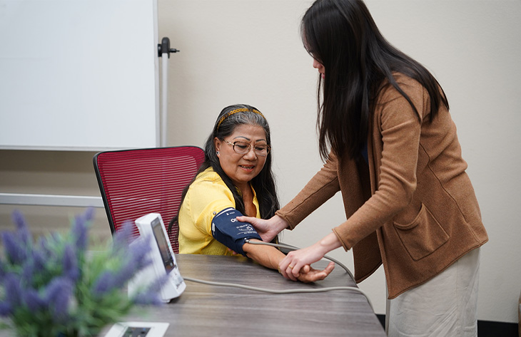  Person measures an older adult’s blood pressure during a health assessment