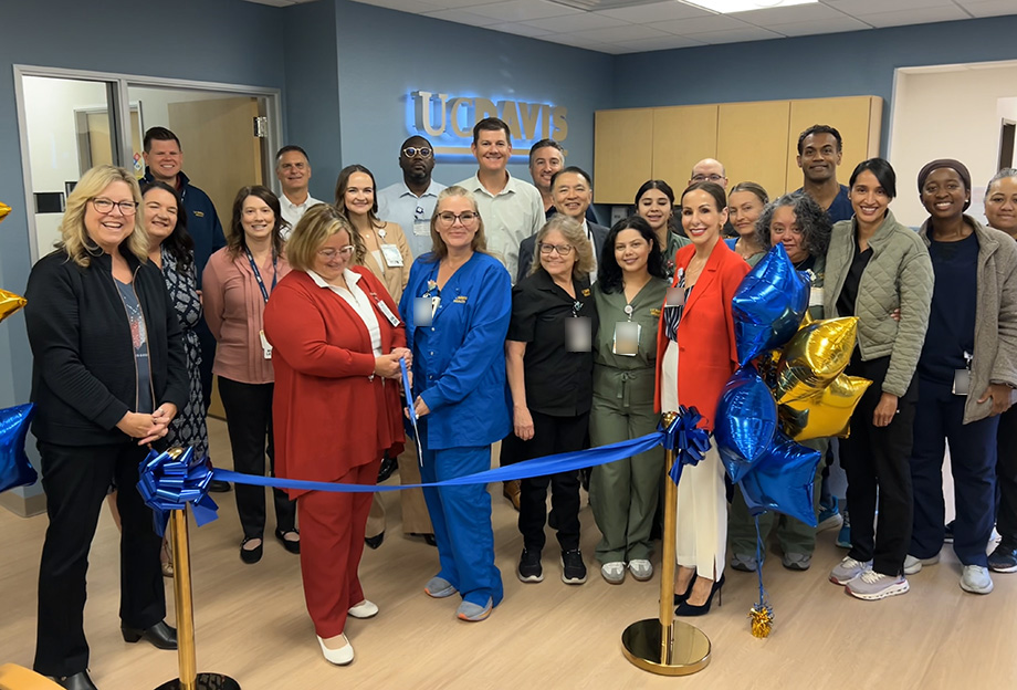 Large group of medical staff in front of blue ribbon, balloons in background
