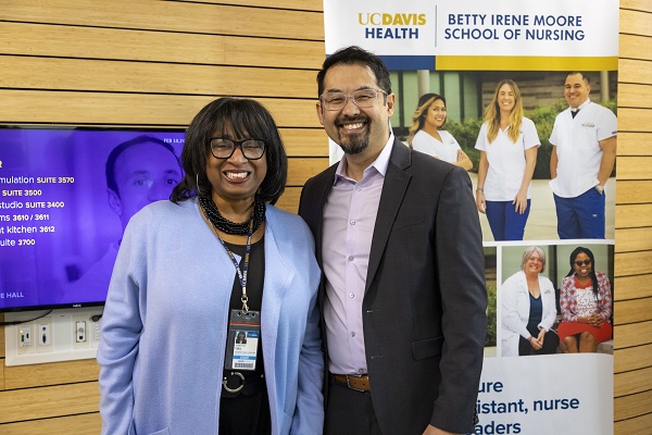 Two people stand in front of a UC Davis Health and Betty Irene Moore School of Nursing display.