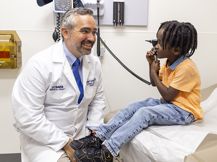 Physician lets child patient play with otoscope in exam room