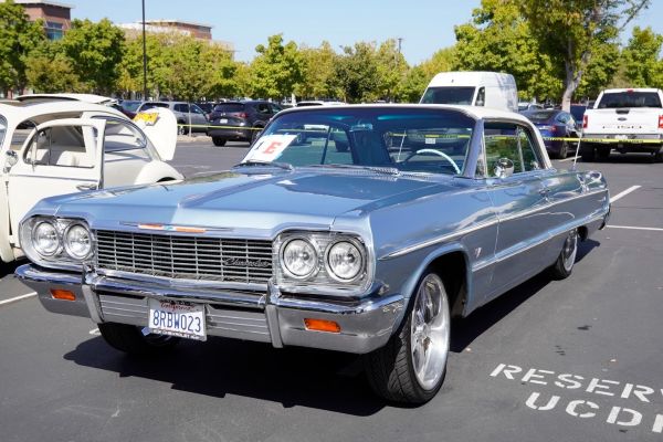 Classic cars lined up at a car show, featuring a blue convertible in the foreground. 